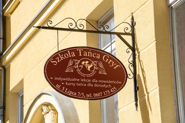 5 Lipca 7 Szkoła tańca Gryf. Klasycznie i elegancko. Bordowy szyld wyróżnia się na tle żółtej kamienicy, ale idealnie współgra stylistycznie. Wydaje mi się wręcz, że bez niego kamienica byłaby "goła".